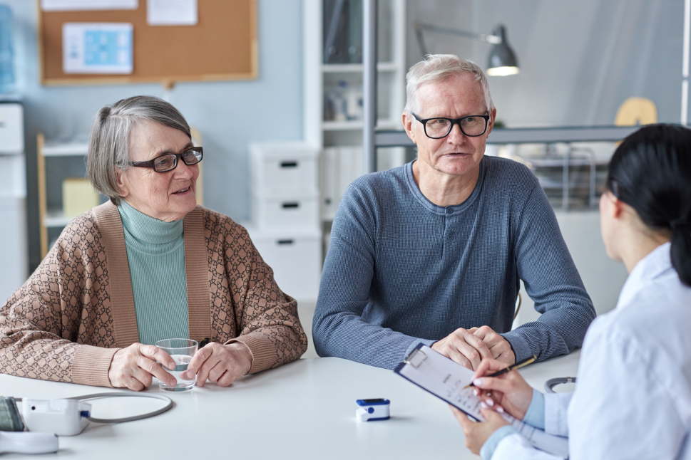 Senior couple discussing Medicare and working past age 65 with their doctor